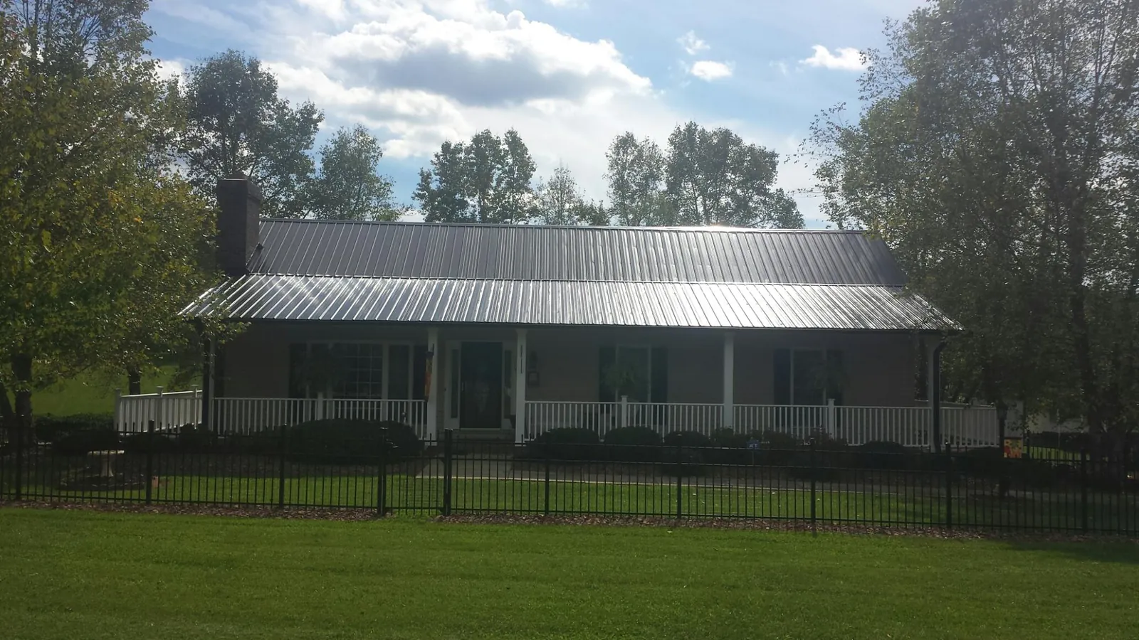 Gray metal roof on a brick ranch with a full width front porch — Gutter Guard Installation work by our crew in Webster